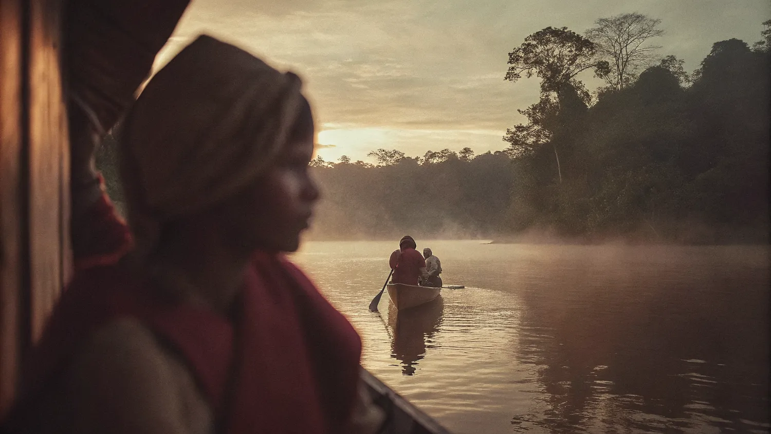 Dawn mist rising over the Amazon river with a small canoe in the distance